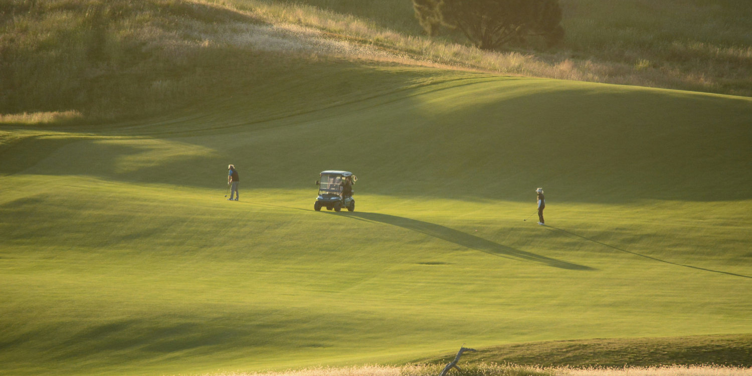 Golfers on a fairway with cart